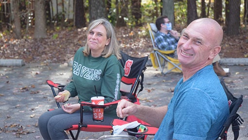 A man and woman sharing a meal outside near tall trees