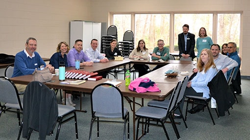 Adults in a classroom sitting around tables