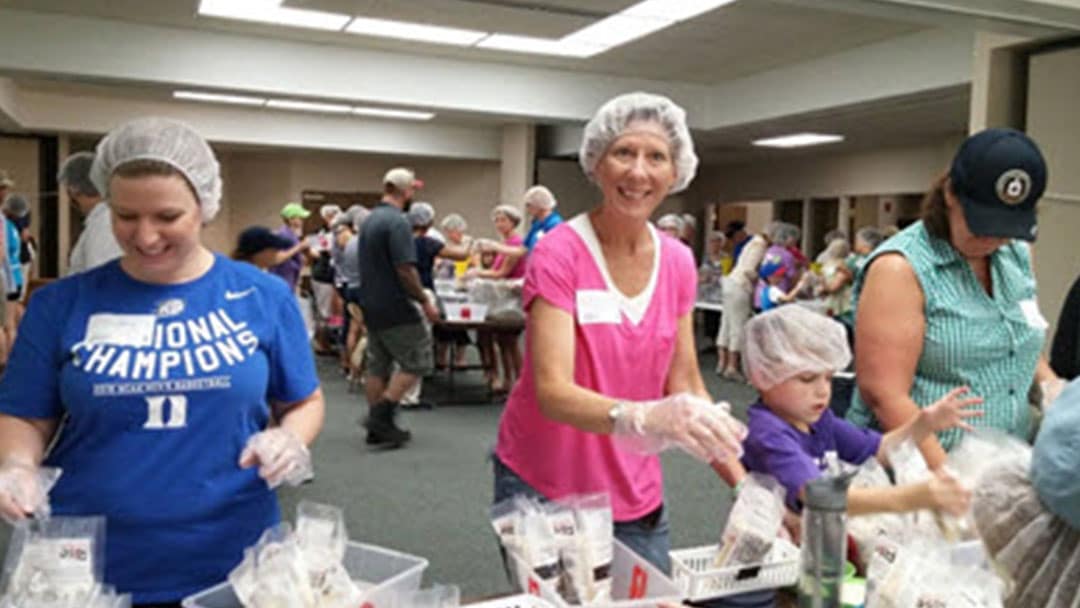 Two ladies serving food smiling