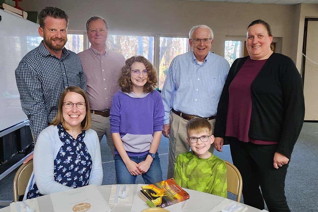 A mom, dad, and two boys sitting a wooden pew together