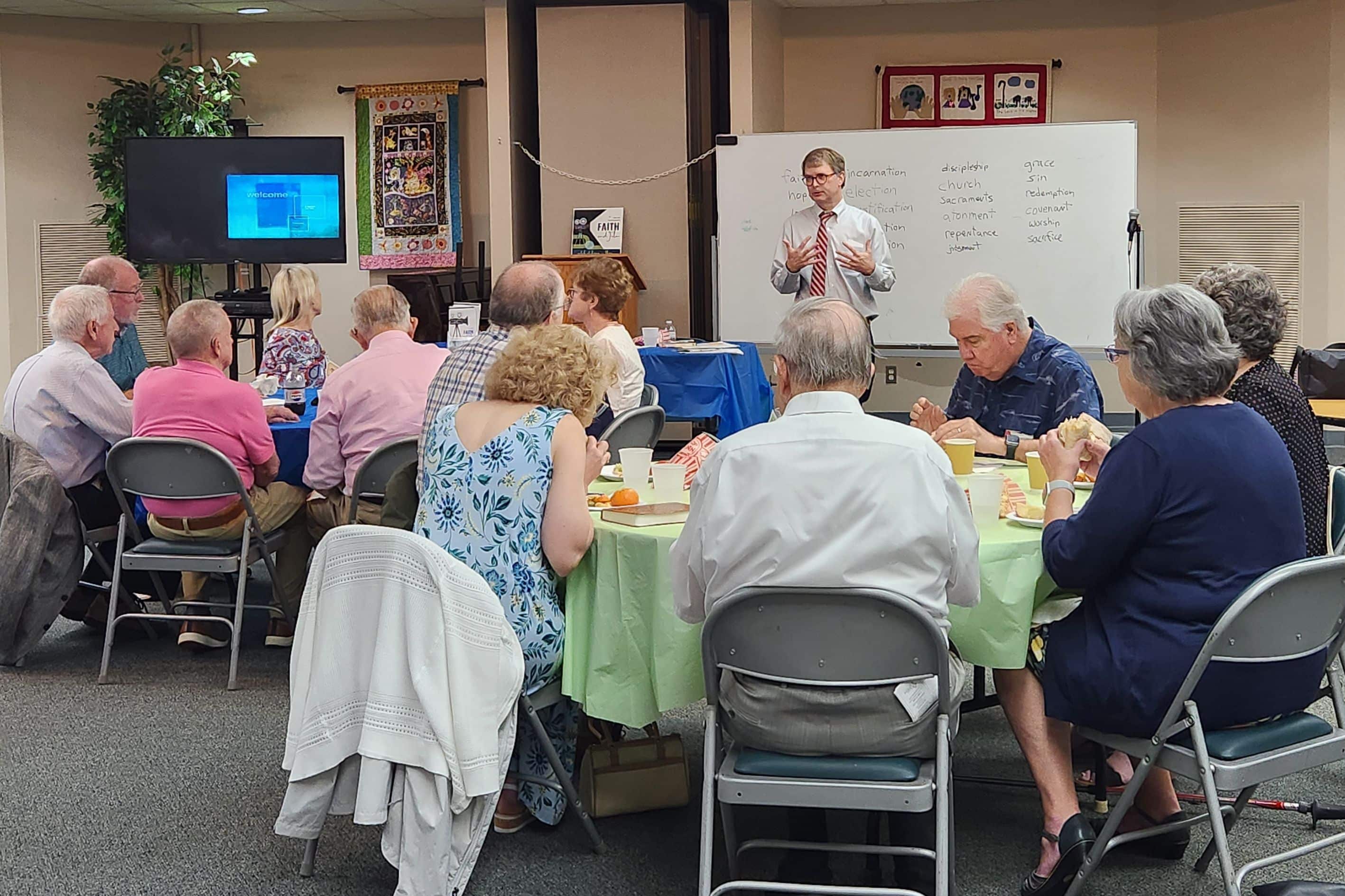 Adults in a classroom sitting around tables